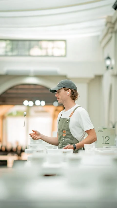 Cole Torode cupping at a Best of Panama table, spoon in hand.